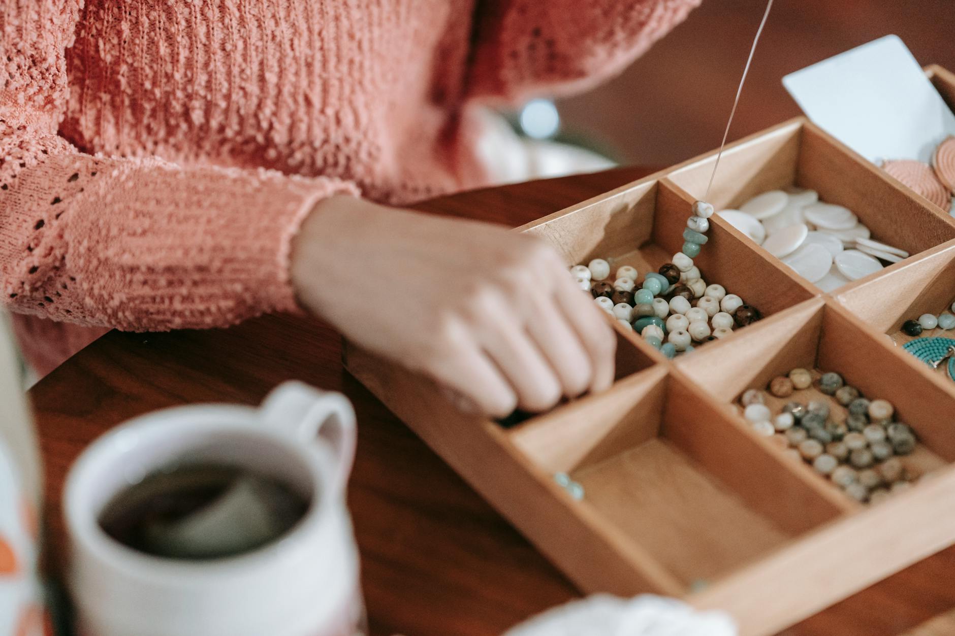 faceless woman making handmade accessory sitting at table