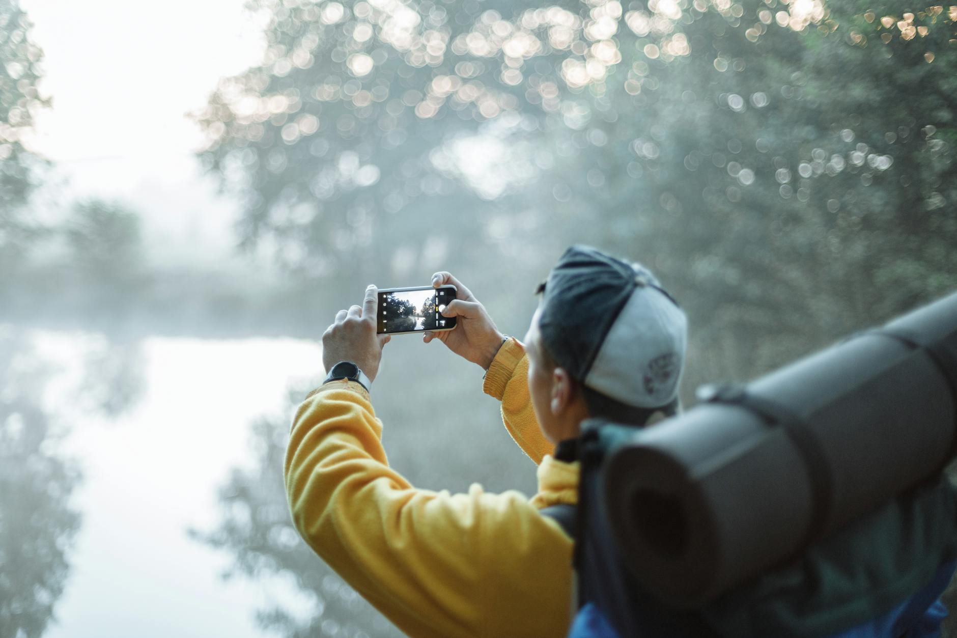 person in yellow jacket taking photo in the forest